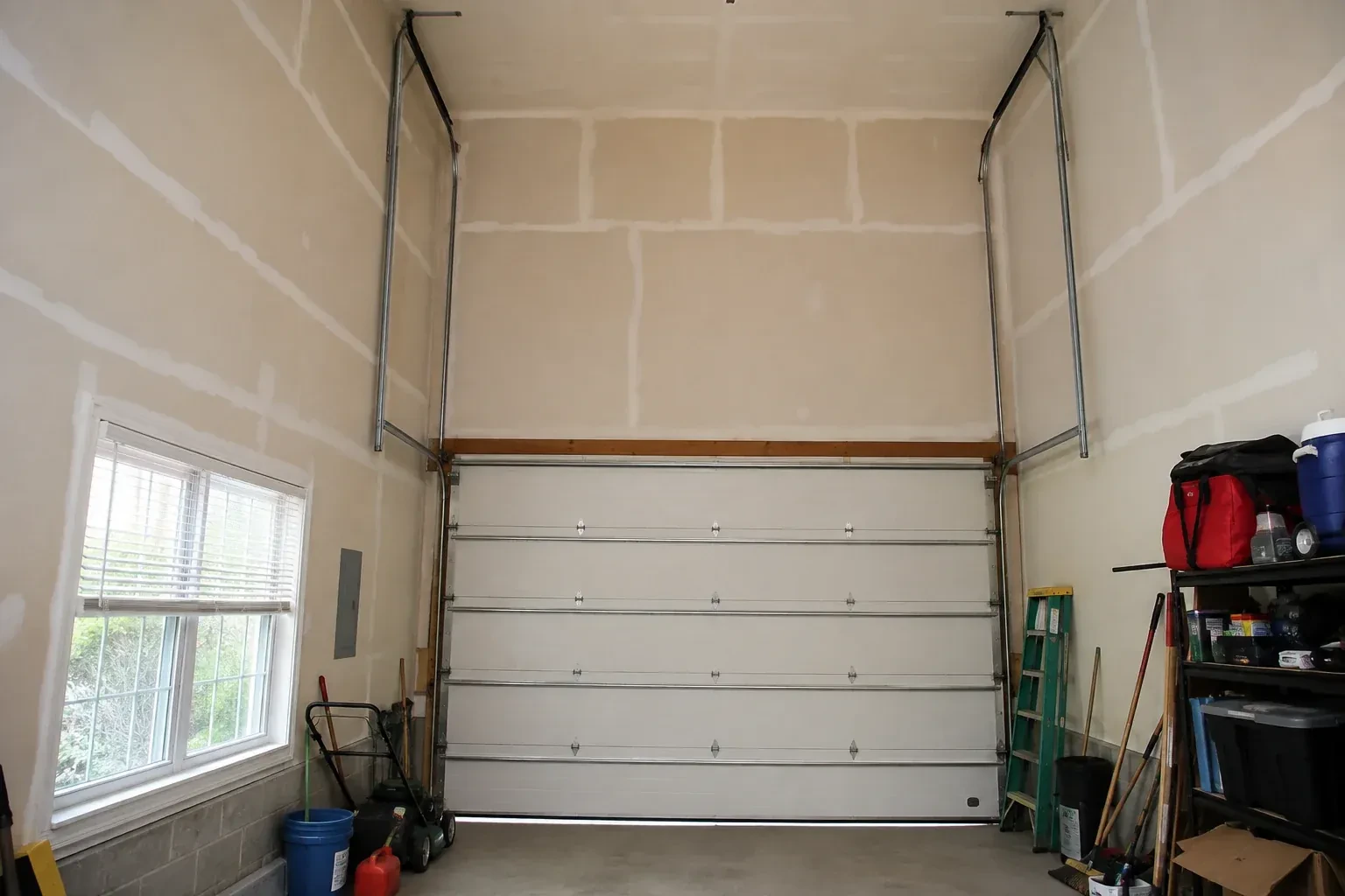 Tall garage interior with a sectional door and tracks extending into overhead space. — High-Lift Garage Door Conversion, Bradford West Gwillimbury